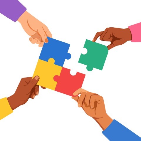 Hands of different people coming together to assemble a colorful puzzle.