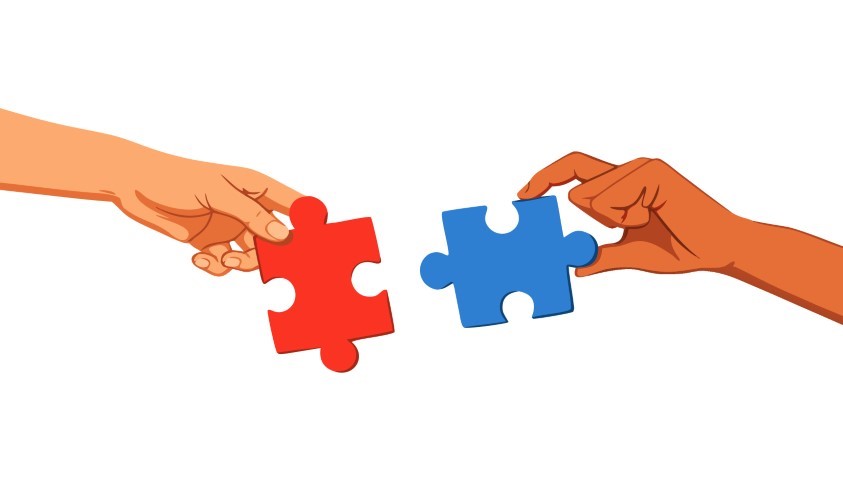 Two hands connecting different colored puzzle pieces in a symbolic gesture.