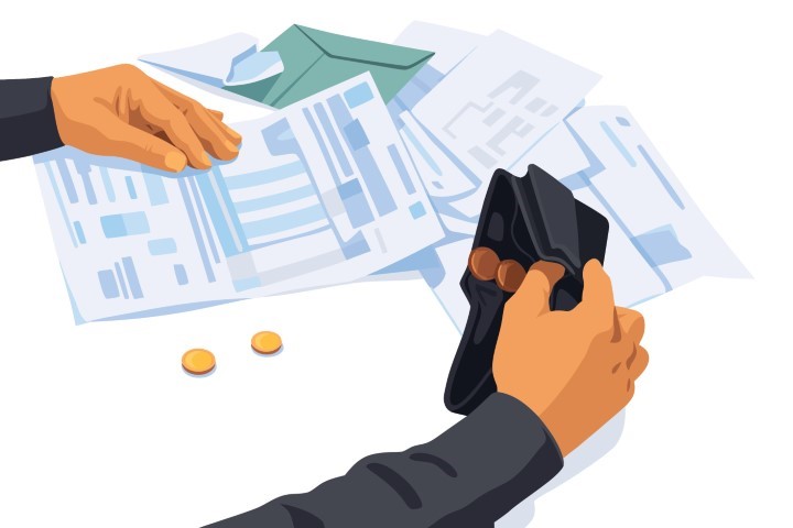 Hand holding an empty wallet with unpaid bills on a table.