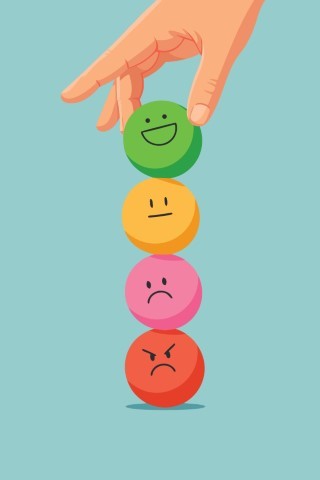 Hand putting a green happy face ball on a stack of emotional spheres.