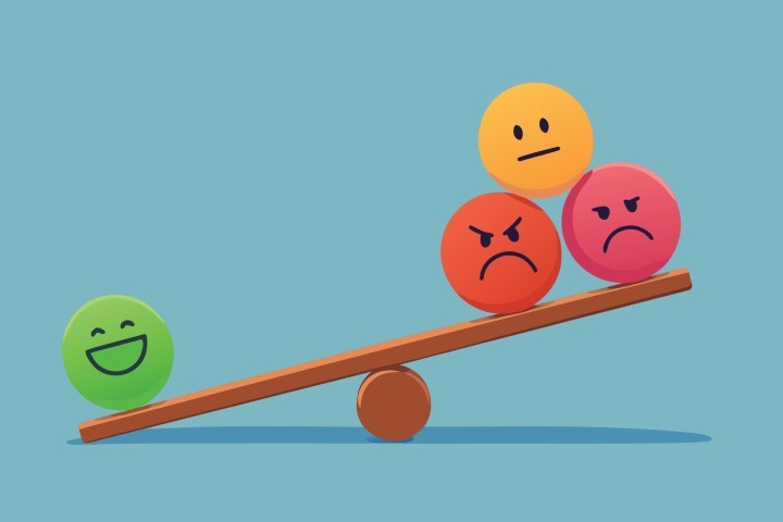 Balance between a single happy face and multiple negative emotion spheres on a seesaw.