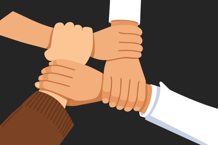 Close up of diverse hands joined together in a circle as a sign of unity.