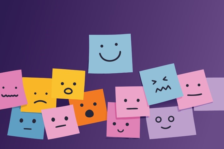 Colorful sticky notes with different facial expressions showing various emotions on wall.