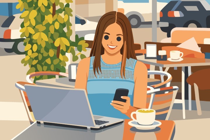 Young woman working on a laptop while sitting at an outdoor cafe terrace.