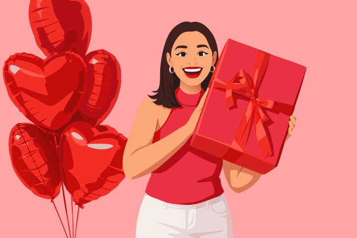 Woman surrounded by many red heart balloons holding a large gift box.