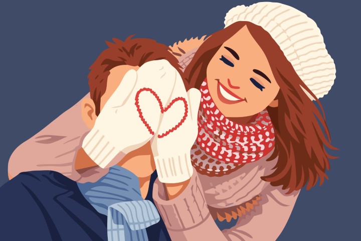 Couple wearing cozy winter clothes and hiding behind a heart-shaped gift.