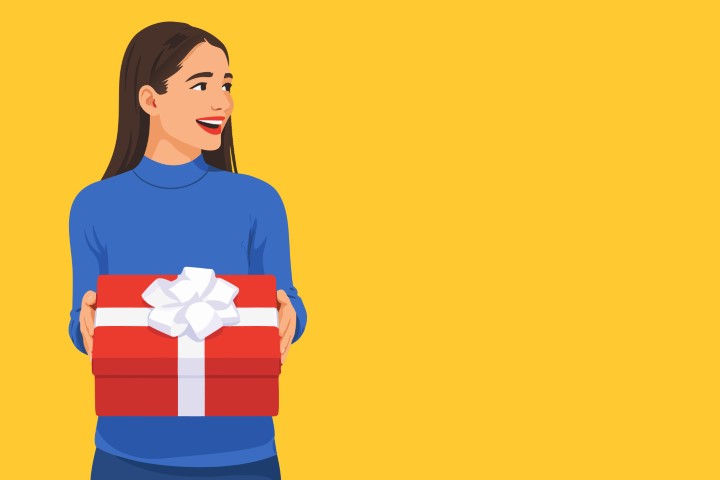 A young woman smiles joyfully while holding a red gift box against a yellow background.
