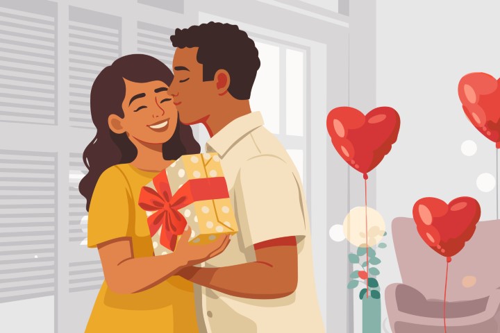A man kisses his partner on the cheek as she holds a yellow gift box.