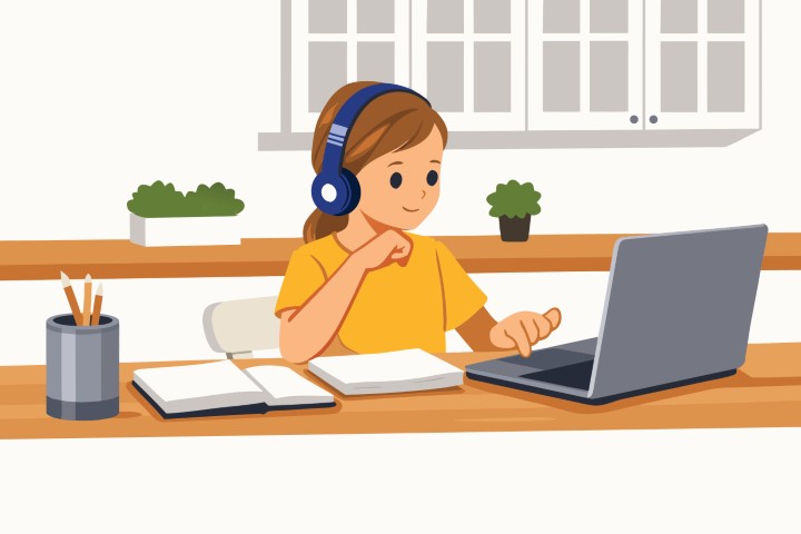 Young student wearing headphones studying with a laptop at home.