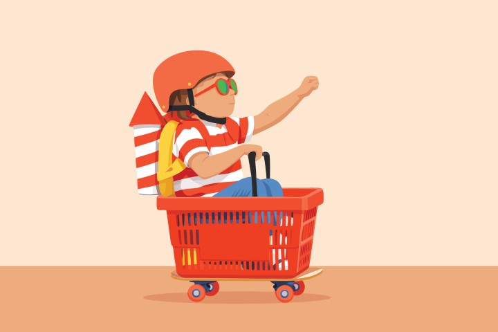 Little child sitting in a red shopping cart and waving happily.