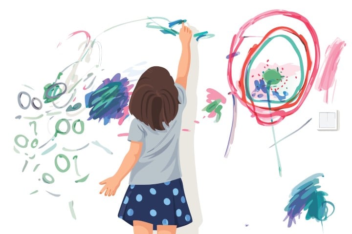 Young girl drawing colorful scribbles on a white wall.