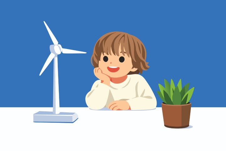 Little girl standing near a small wind turbine model and a plant.