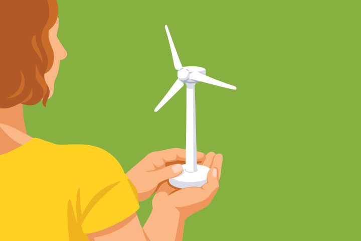 Woman holding a small wind turbine model representing clean energy.