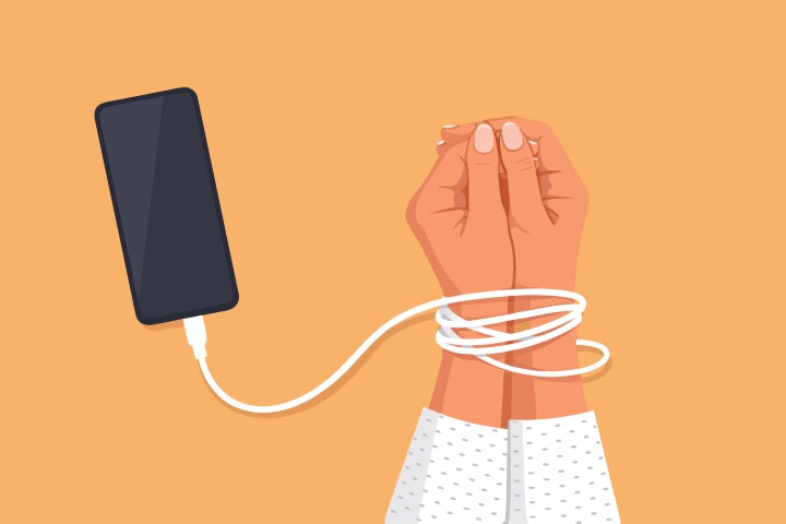 Hand tied with a charging cable to a smartphone representing digital addiction.
