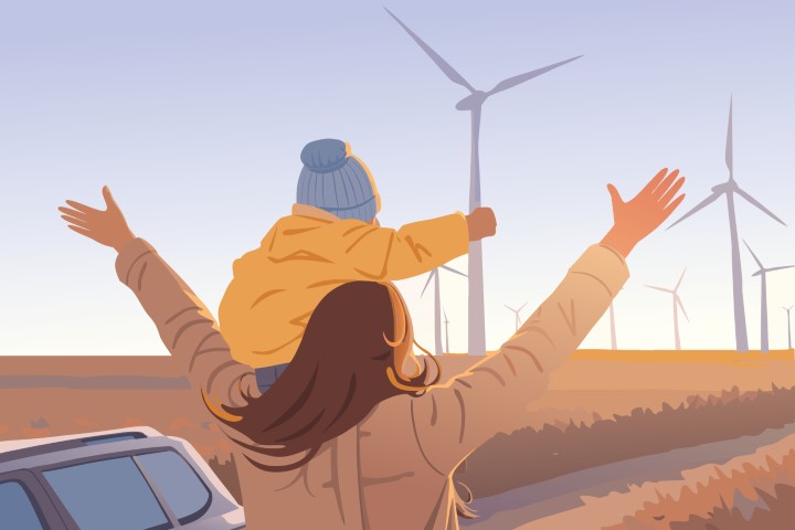 Happy family enjoying a beautiful sunset near a wind farm.